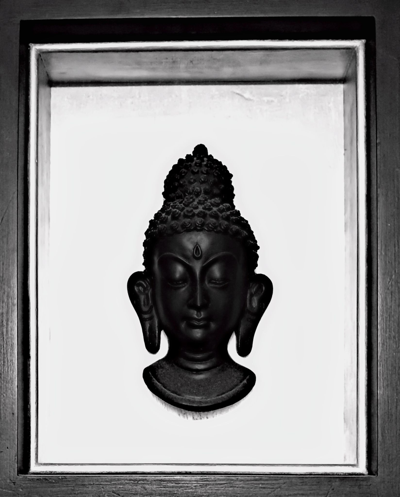 Black Buddha head in a deep wooden frame, the study